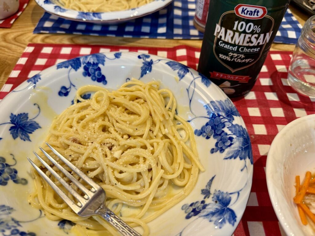 キューピーあえるパスタソースのカルボナーラに粉チーズを振っていることが分かる画像