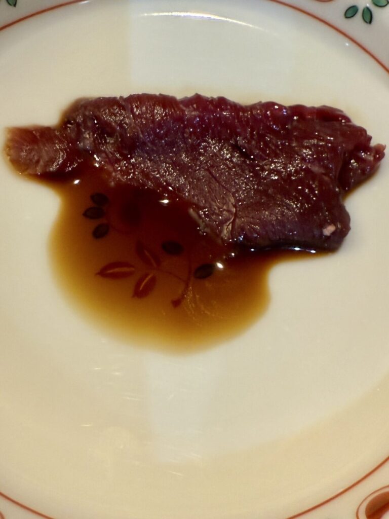 馬刺しをたれにつけたところを撮った画像