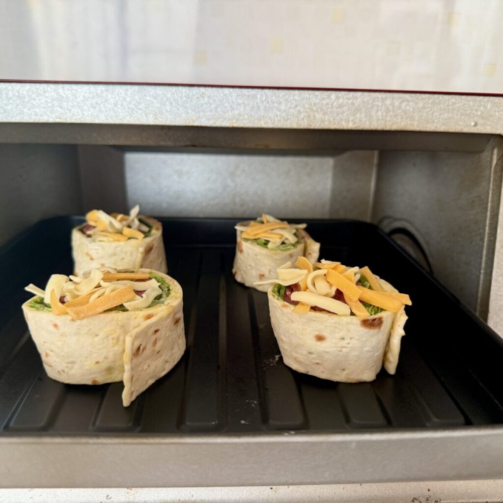 ローストビーフハイローラーにマーブルシュレッドチーズをのせてオーブントースターに入れたところを撮った画像