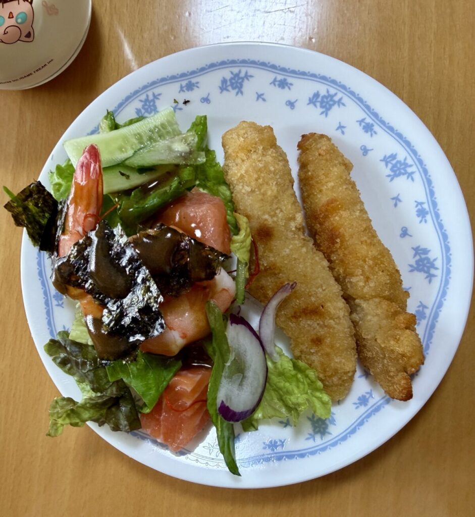 サーモン＆シュリンプチョレギサラダとチキンスティックを皿に盛り付けた画像